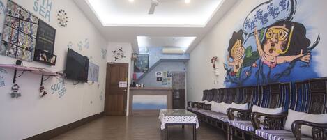 A room with a long bench seating area, a table with a tablecloth, and a mural on the wall.