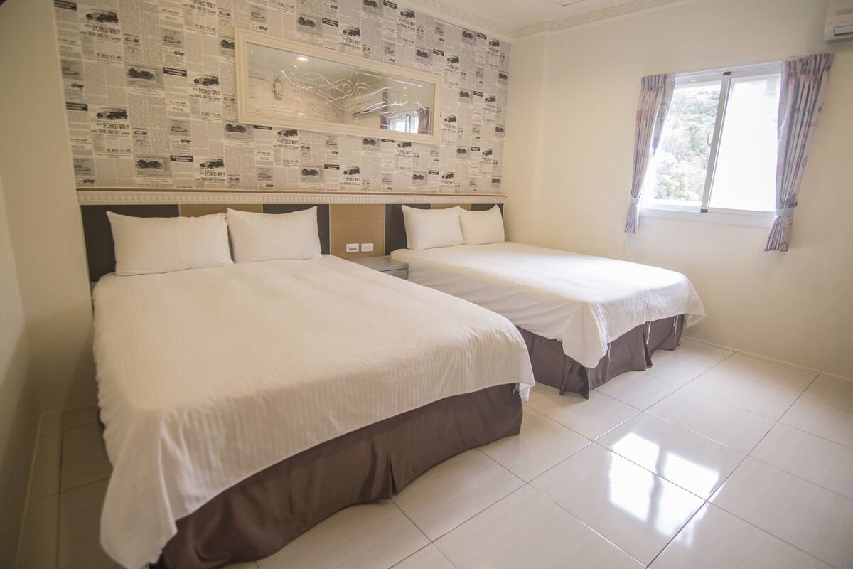 Habitación de hotel con dos camas, un espejo grande y una ventana con cortinas.
