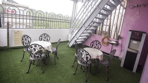 A terrace with artificial grass, metal chairs, a table, a staircase, and a kitchen area. - SouthSea B&B (Liuqiu)