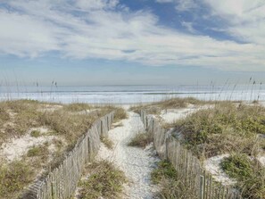 A sandy path leading to a beach with a wooden fence and sparse vegetation. - Sandpiper 222 - No Shoes, No Shirt, No Worries! (St. Augustine)