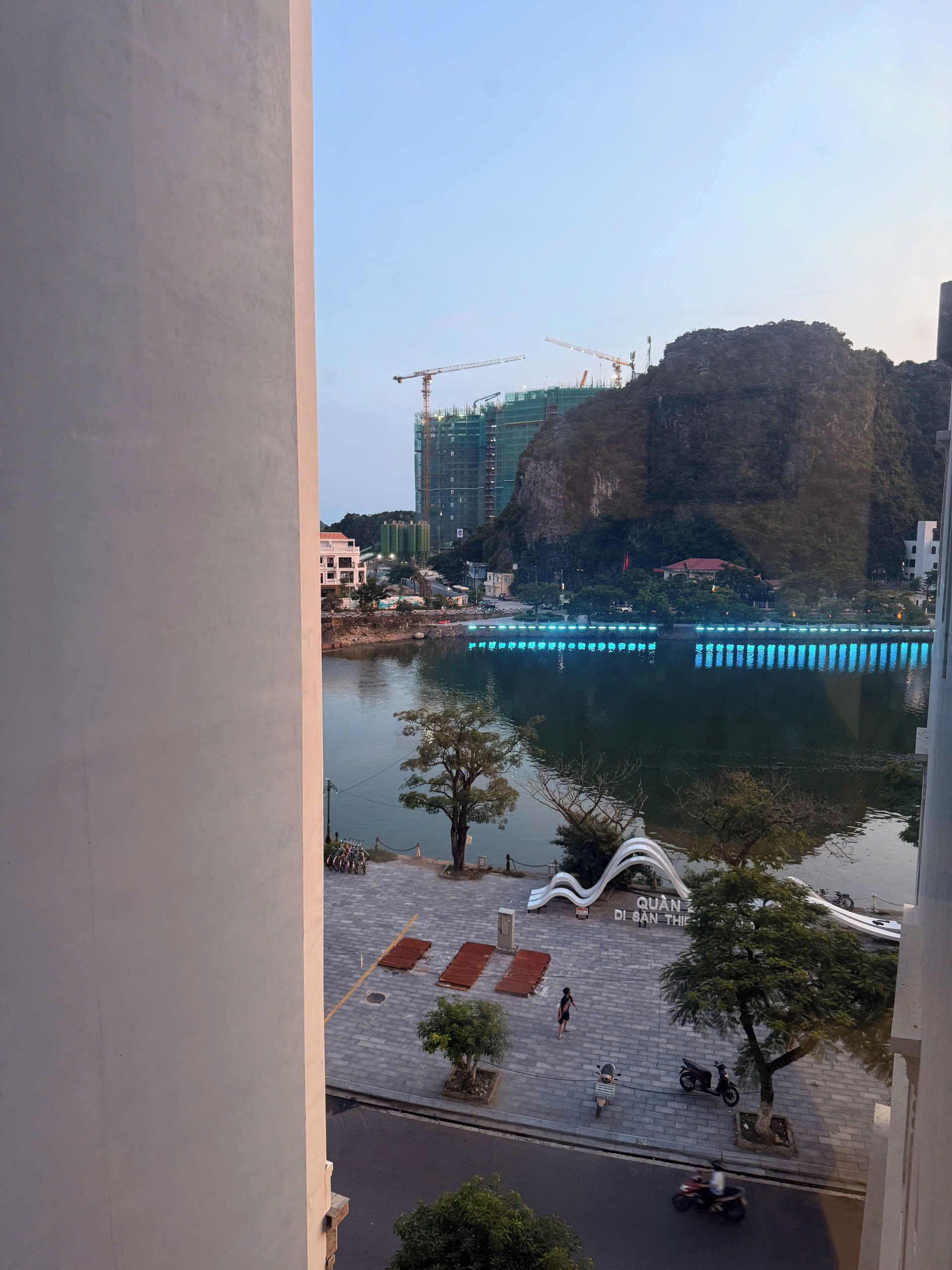 A view of a waterfront area with a construction site, a bridge, and a pedestrian walkway.