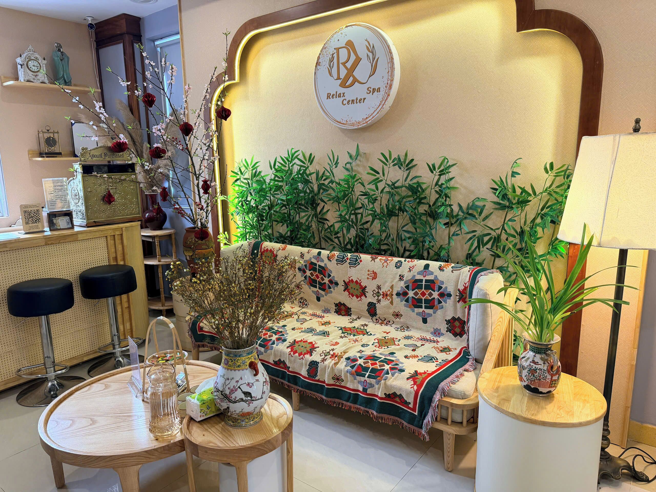A reception area with a sofa, chairs, a table, a vase with flowers, and a sign indicating a Relax Center Spa.