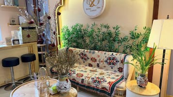 A reception area with a sofa, chairs, a table, a vase with flowers, and a sign indicating a Relax Center Spa.