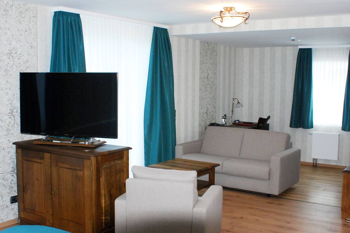 A living room with a flat-screen TV, a sofa, a wooden cabinet, and a table.
