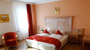 A bedroom with a bed, a chair, a nightstand, a lamp, and a painting on the wall. - Rüter's Hotel & Restaurant (Salzhausen)