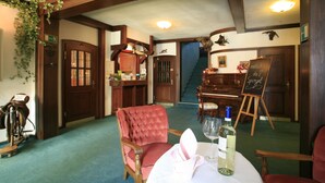 A room with a dining table set for two, a piano, and a staircase leading to another level. - Rüter's Hotel & Restaurant (Salzhausen)