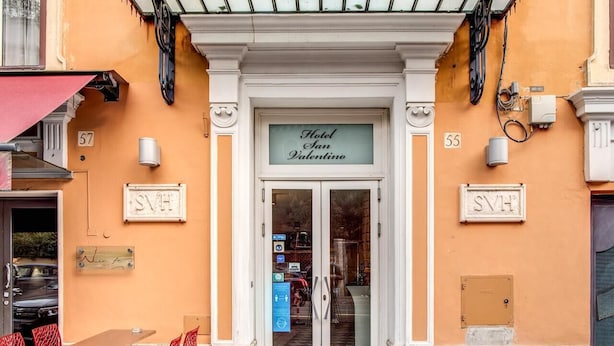 The entrance to Hotel San Valentino with a sign above the door, a small outdoor seating area with red chairs, and a number '55' on the wall. - San Valentino (Rome)
