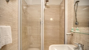 A modern bathroom with a glass-enclosed shower, a white sink, and a glass shelf with toiletries. - San Valentino (Rome)