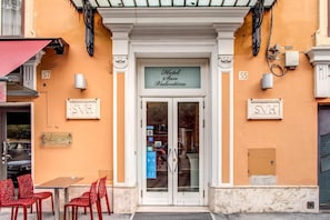 The entrance to Hotel San Valentino with a sign above the door, a small outdoor seating area with red chairs, and a number '55' on the wall. - San Valentino (Rome)