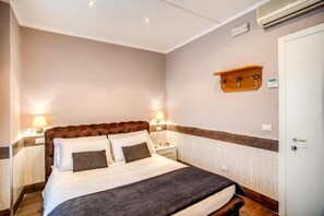 A neatly arranged bedroom with a large bed, bedside lamps, a wooden shelf, and a door. - San Valentino (Rome)