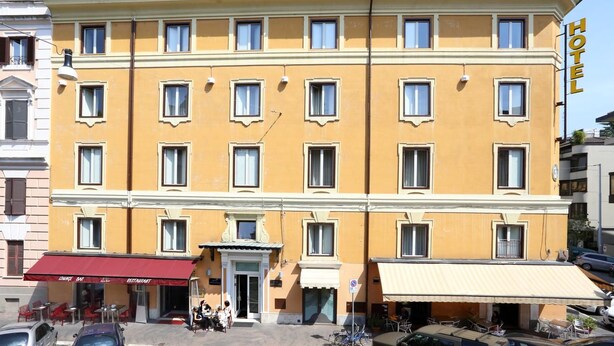 Un hôtel jaune avec un auvent rouge, de nombreuses fenêtres et une enseigne indiquant qu’il s’agit d’un hôtel.