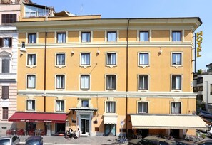 Un hôtel jaune avec un auvent rouge, de nombreuses fenêtres et une enseigne indiquant qu’il s’agit d’un hôtel.