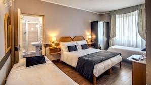 Une chambre d’hôtel avec deux lits, une douche, une coiffeuse avec un miroir et un téléviseur.