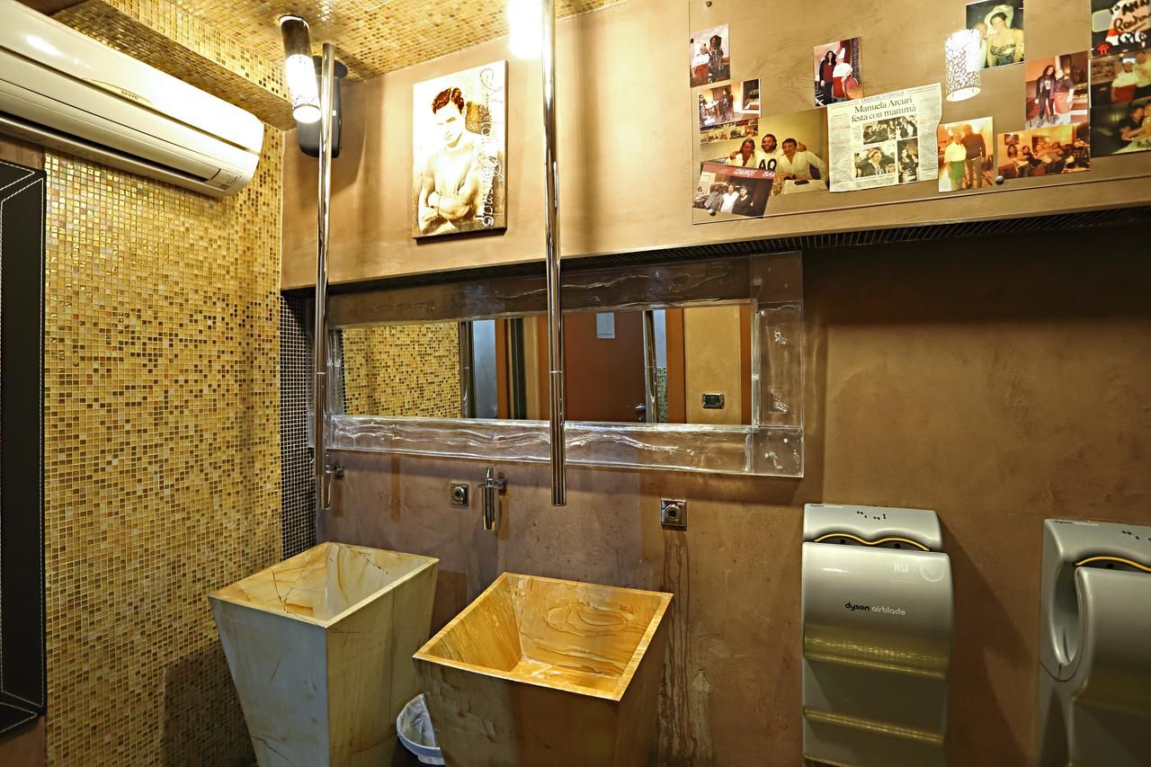 A restroom with a tiled wall, a mirror, a sink, and a Dyson airblade hand dryer.