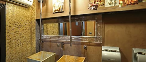A restroom with a tiled wall, a mirror, a sink, and a Dyson airblade hand dryer.