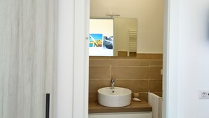 A bathroom with a round sink, a mirror above it, and a towel hanging on a rack.