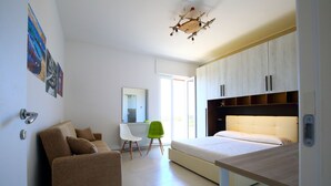 A modern bedroom with a bed, a desk, a sofa, and a chair.