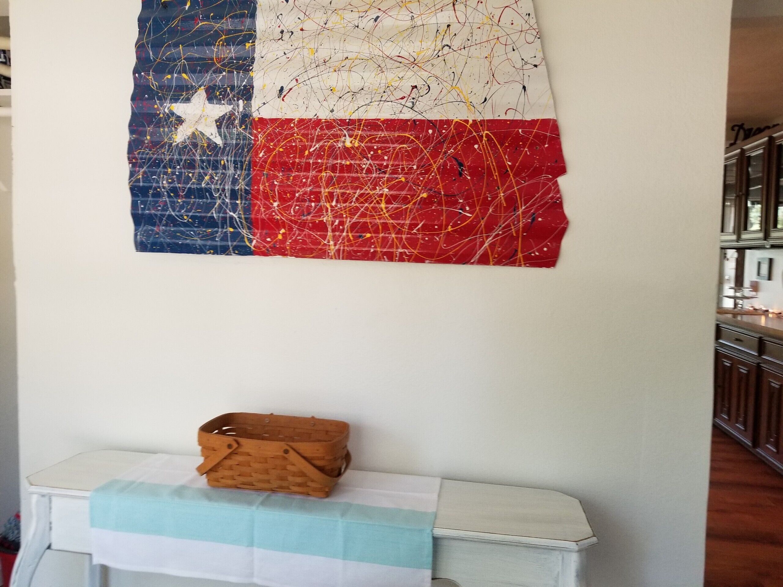 Een muur met een schilderij van de Texas vlag en een klein houten mandje op een tafel.