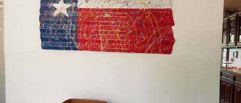 Een muur met een schilderij van de Texas vlag en een klein houten mandje op een tafel.