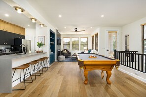 Une cuisine moderne avec des tabourets de bar, une table de billard et un coin repas comprenant un canapé et une table.