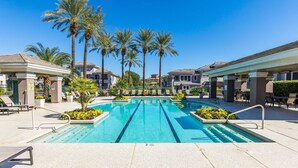 Une piscine à l’eau d’un bleu cristallin, entourée de palmiers et de chaises longues.