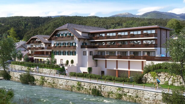 Un hotel de varios pisos con balcones, un muro de piedra y un río al frente.