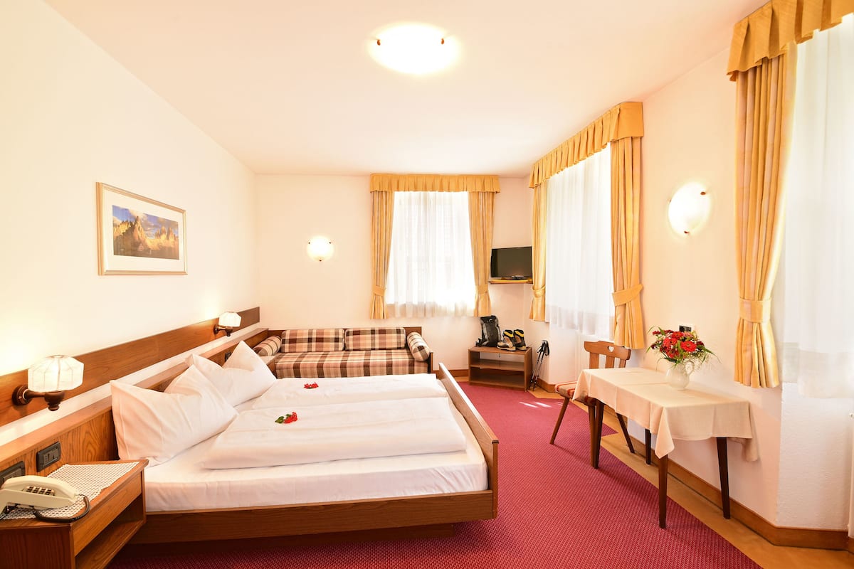 A hotel room with two beds, a desk, a chair, a TV, and a telephone.