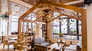 Un intérieur chaleureux avec des poutres apparentes, un espace salon aménagé à la manière d’un loft et de grandes fenêtres offrant une vue sur la ville.