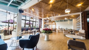 Un espace intérieur vaste et lumineux, avec des poutres en bois au plafond, de grandes fenêtres et un mobilier moderne.