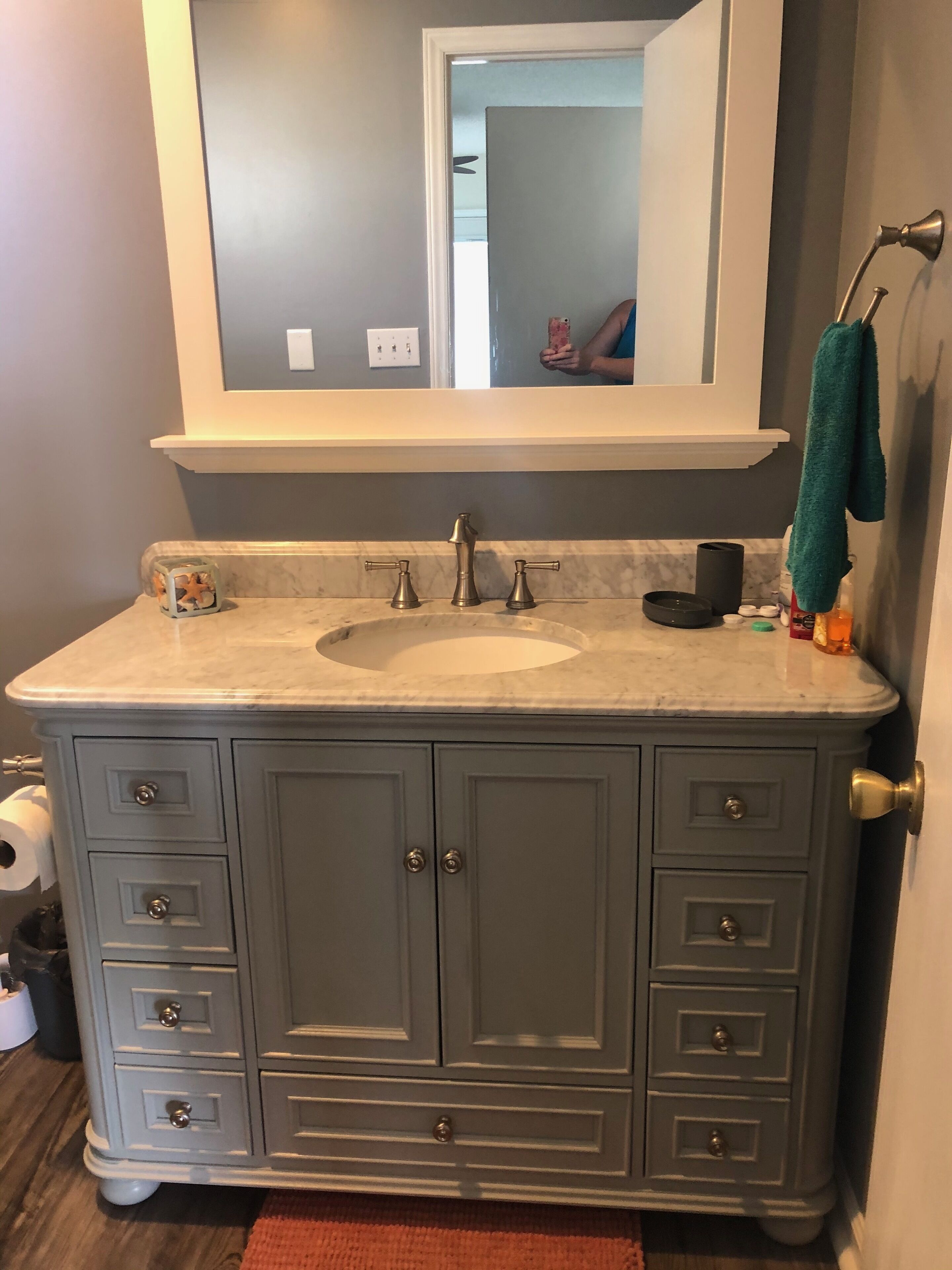 A bathroom with a marble sink, a large mirror, and grey cabinetry.