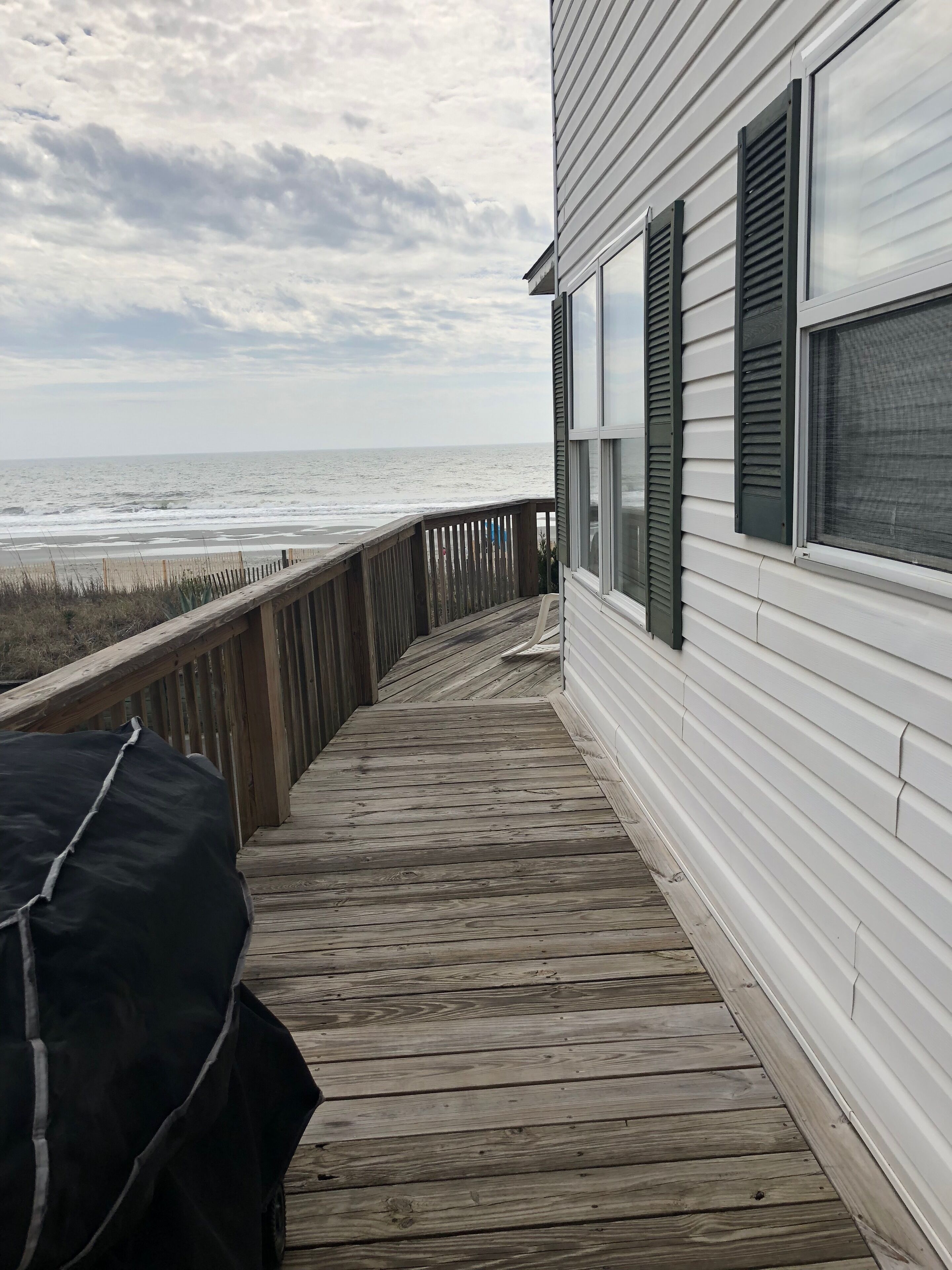A wooden deck leading to a house with a view of the ocean.