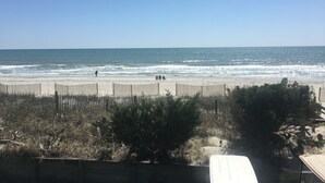 Een strand met een houten omheining, enkele mensen en een heldere lucht.