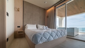 Un dormitorio moderno con una cama grande, cabecera de madera y vista al océano.