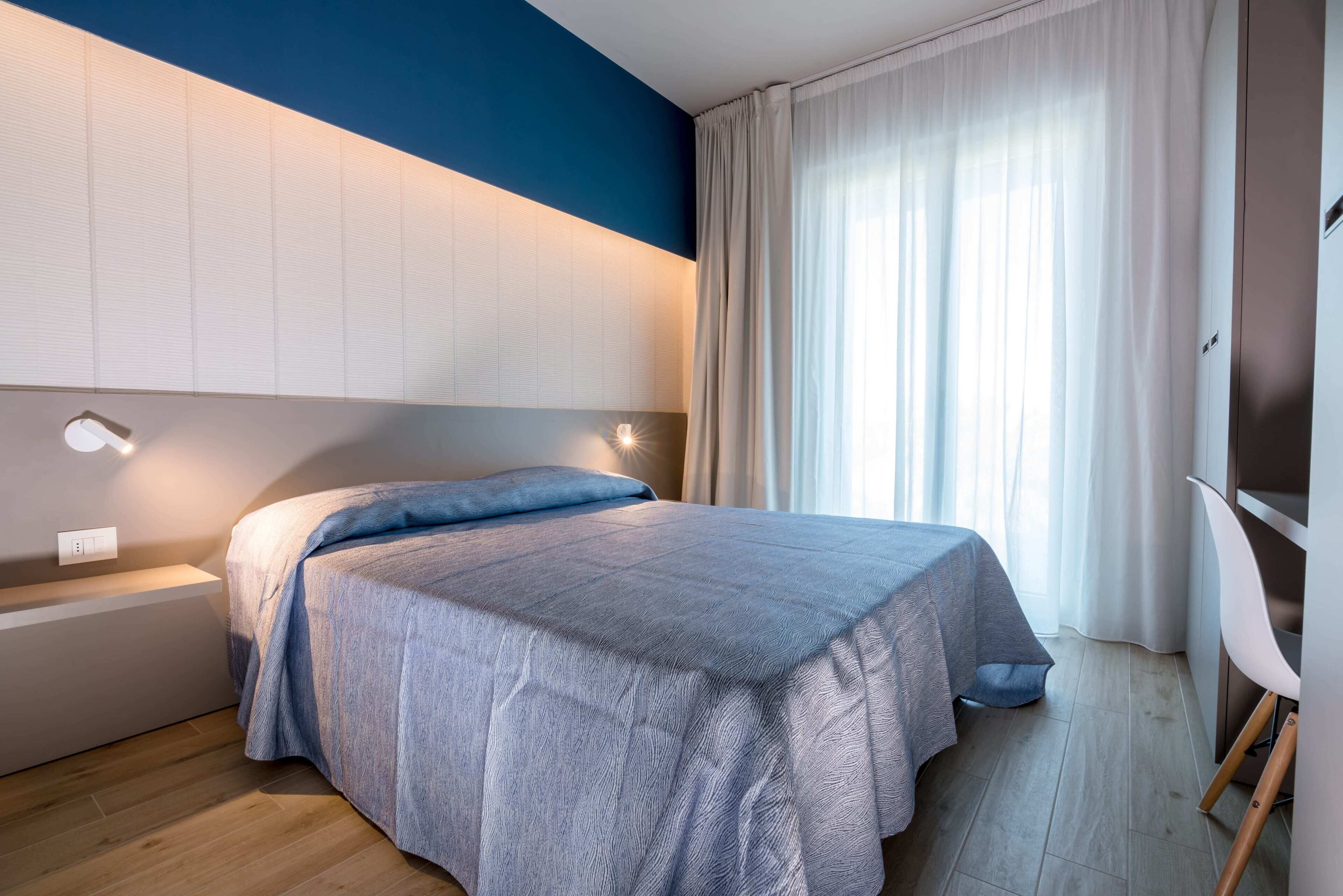 Un dormitorio moderno con cama, mesitas de noche, escritorio y silla.