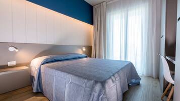 Un dormitorio moderno con cama, mesitas de noche, escritorio y silla.