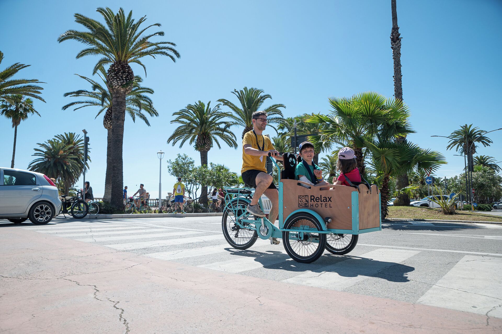 A person riding a bicycle with a cart labeled "Relax Hotel".