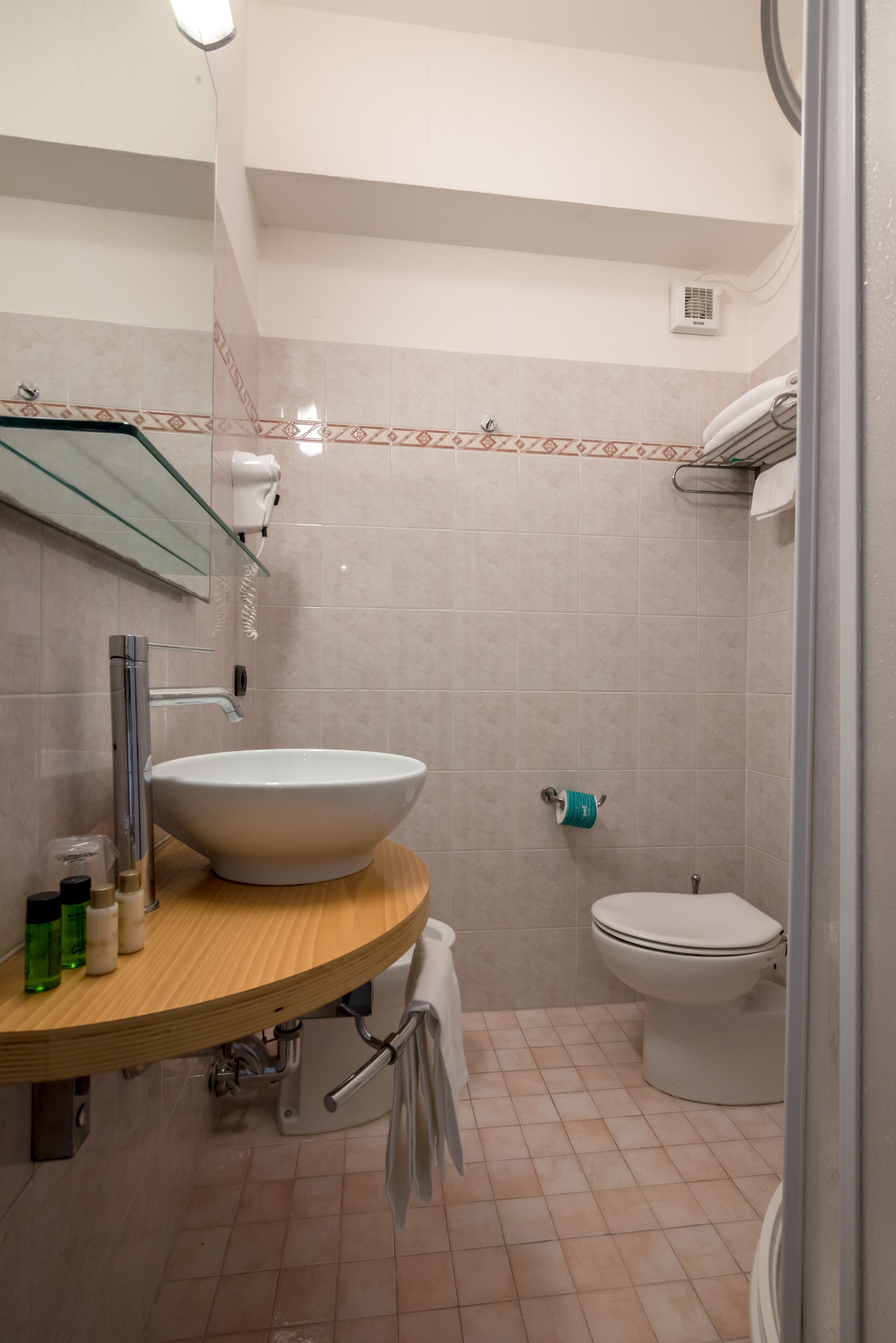 A bathroom with a round sink, a toilet, and a glass shower enclosure.