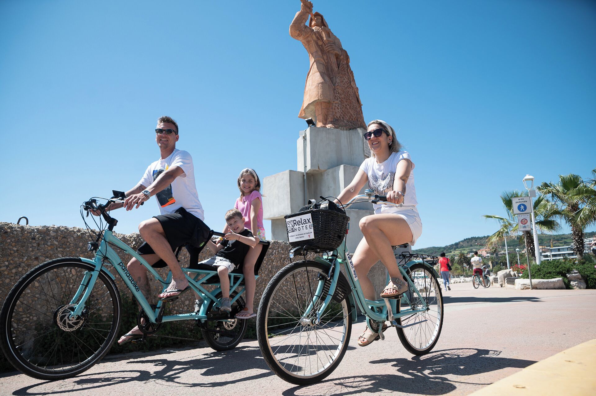 A group of people on bicycles with a statue in the background.