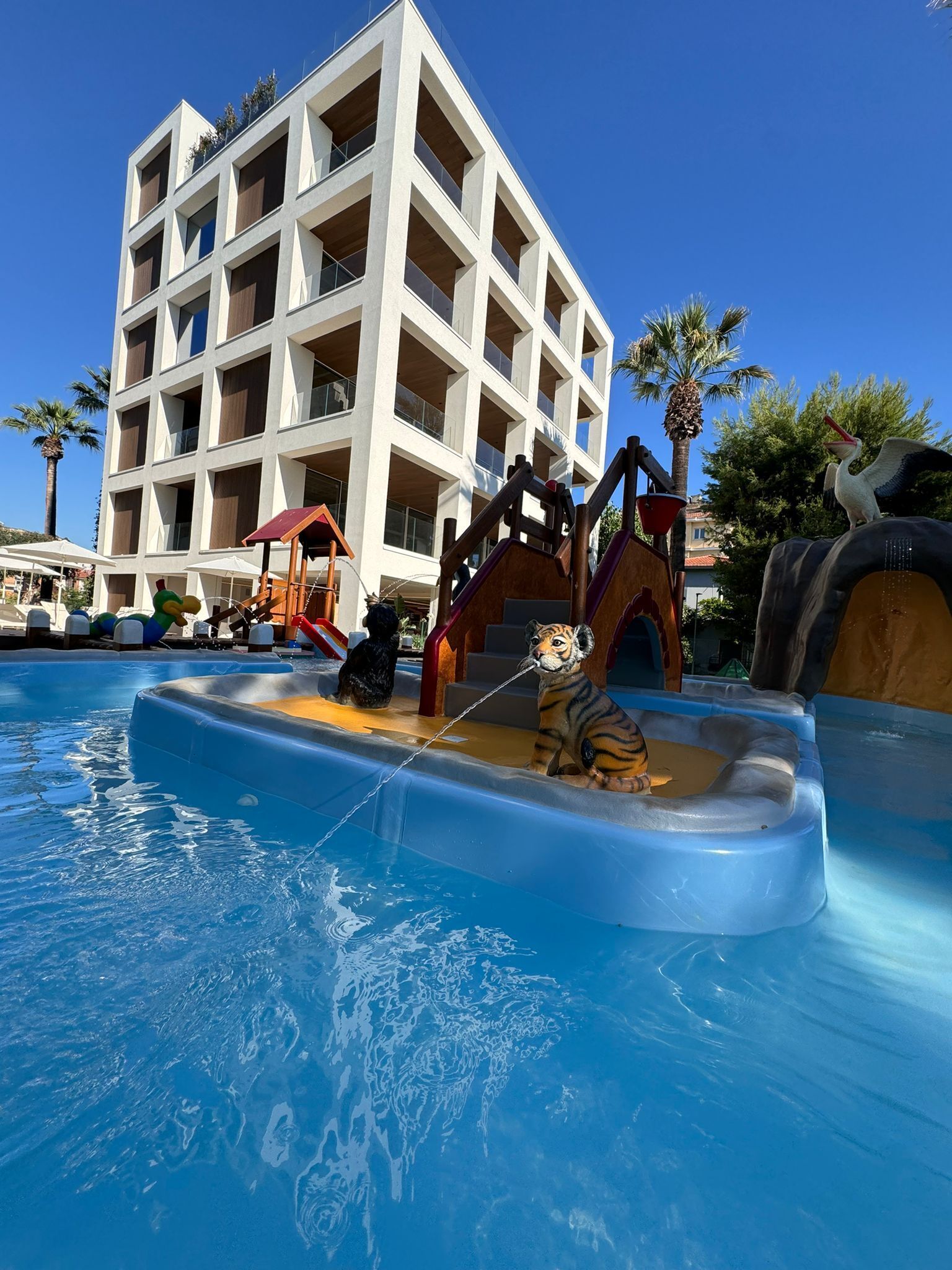 Ein Wasserpark mit Pool, Rutschen und einem Gebäude im Hintergrund.