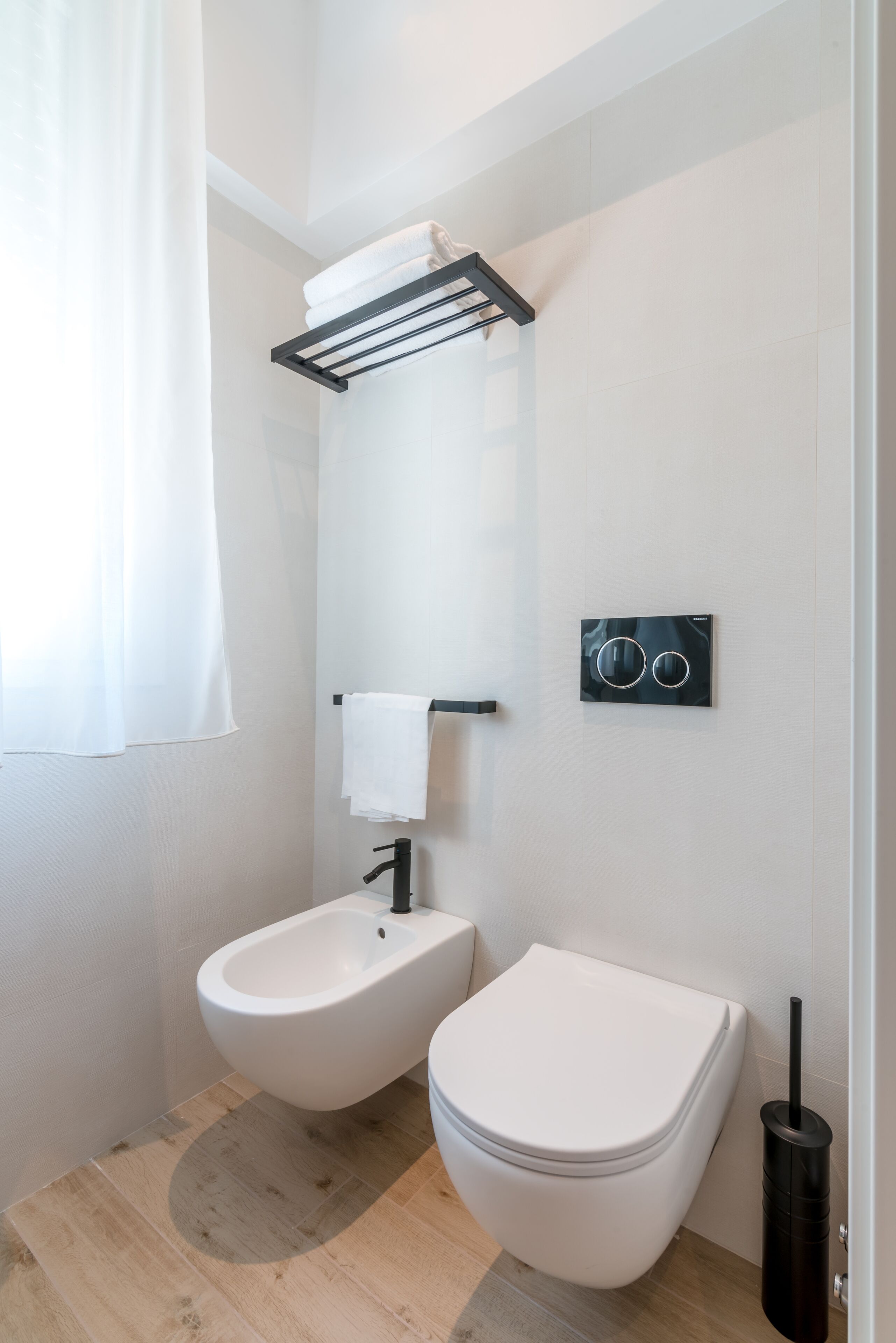 Een moderne badkamer met een bidet, toilet, handdoekrek en bedieningspaneel.