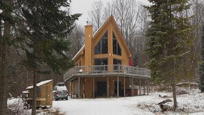 Une cabane dotée d’un balcon, entourée d’arbres et de neige.