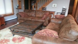 Un salon avec un canapé en cuir marron, un fauteuil assorti et une table basse en bois.