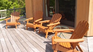 Une terrasse en bois avec quatre chaises Adirondack et une petite table.