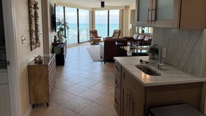 Una cocina amplia con una isla grande, un comedor con vista al océano y una sala de estar con un ventanal que da al mar.
