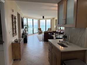 Una cocina amplia con una isla grande, un comedor con vista al océano y una sala de estar con un ventanal que da al mar.