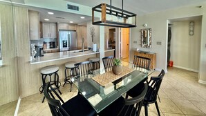 Una cocina moderna con una isla central, taburetes de bar y una mesa de comedor con sillas.