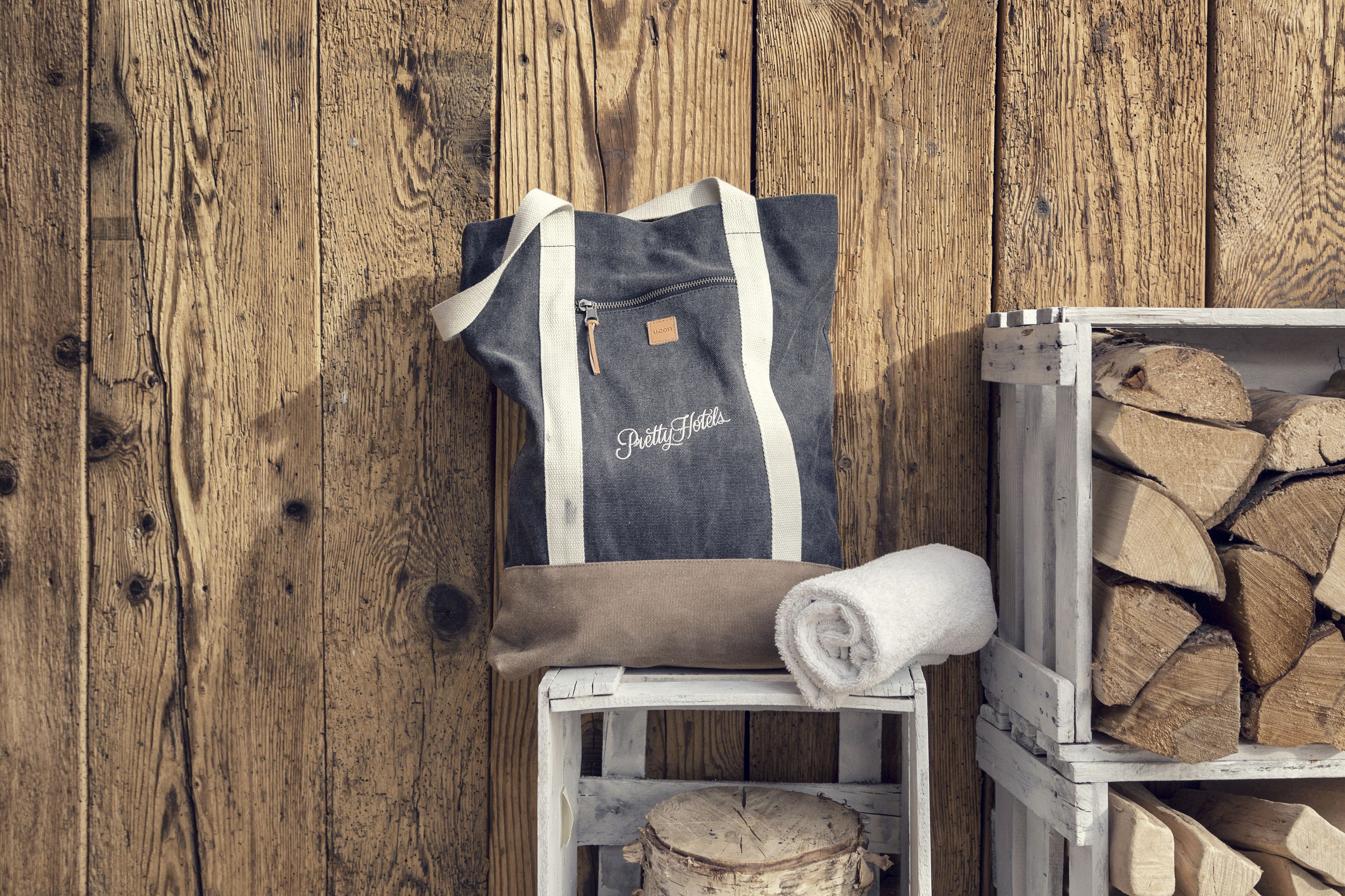 A wooden wall, a grey and white bag with "Pretty Hotels" text, and a stack of firewood.