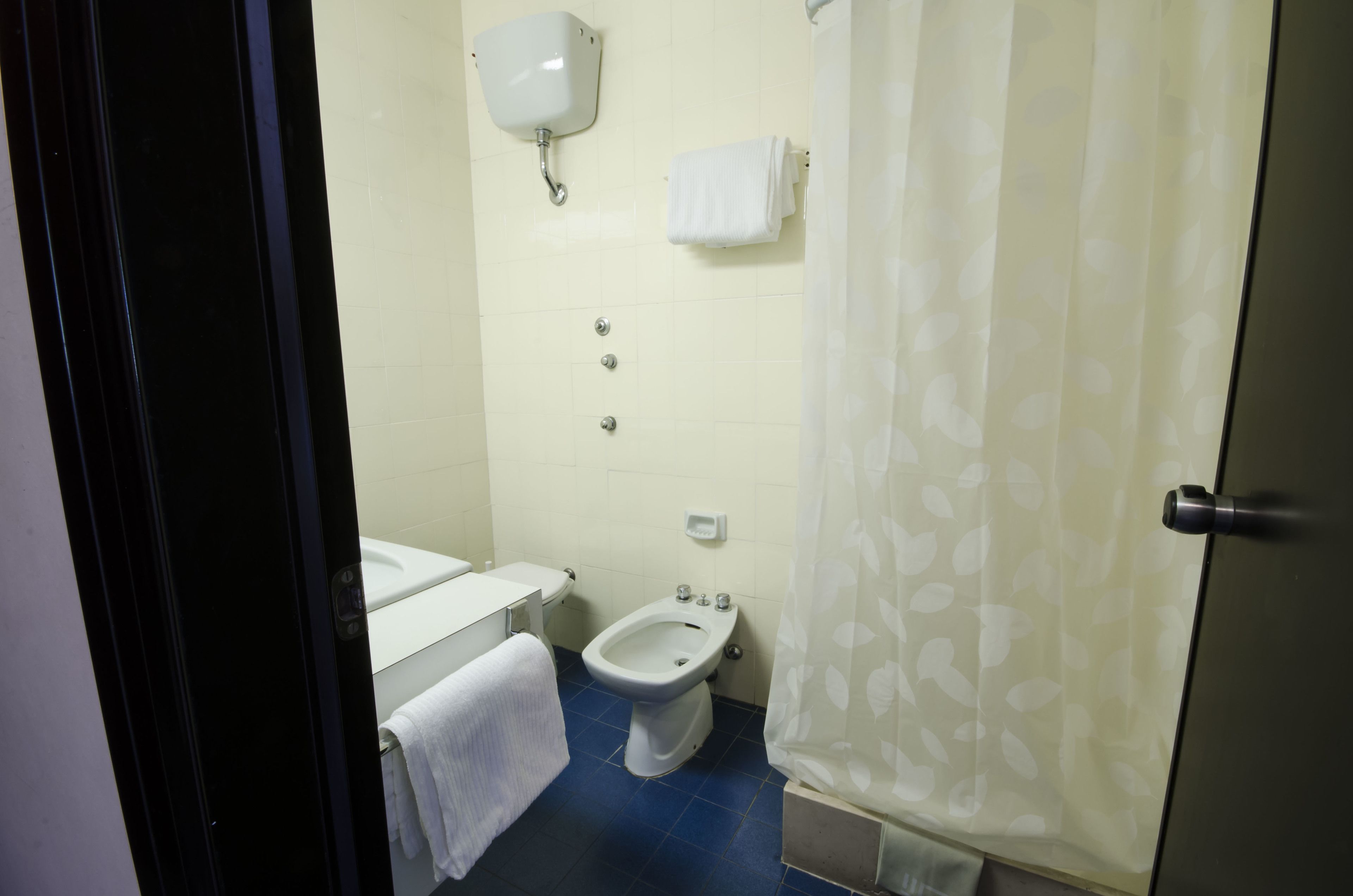 Un baño con inodoro, bidé y un perchero para toallas.