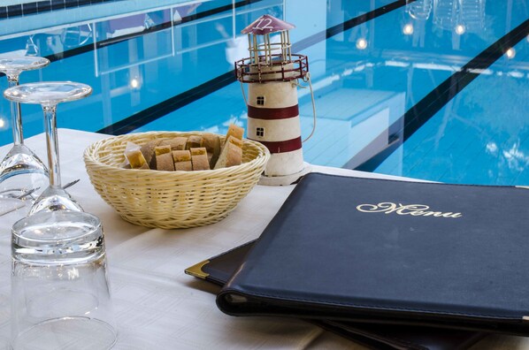 A table with a wicker basket containing bread, a menu, and a glass jar.
