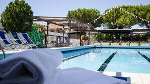 A swimming pool with lounge chairs and a covered area. - Hotel Helios (Tarquinia)